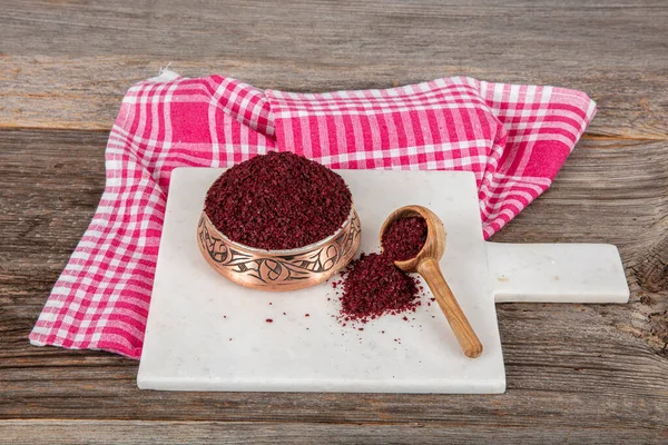 Tahta kaşıkta kuru baharatlı sumak. Yer sumac baharatı. Kurutulmuş kırmızı Sumac tozu, ahşap kaşıkta, kırsal masada sumak üzümlü baharatlar. Sağlıklı gıda konsepti.
