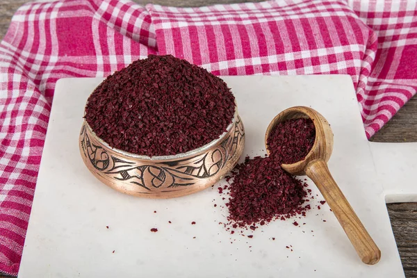 Tahta kaşıkta kuru baharatlı sumak. Yer sumac baharatı. Kurutulmuş kırmızı Sumac tozu, ahşap kaşıkta, kırsal masada sumak üzümlü baharatlar. Sağlıklı gıda konsepti.