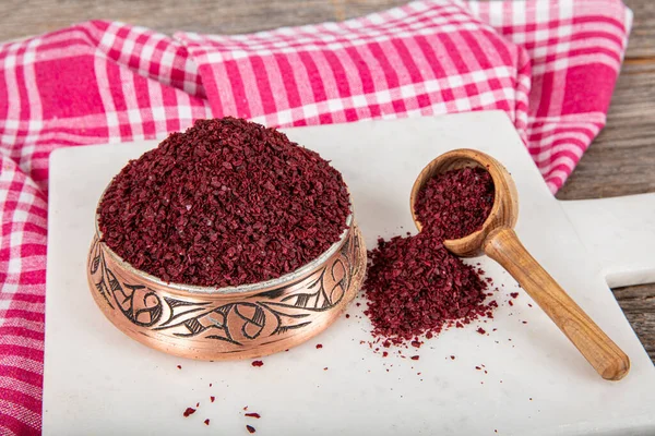 Tahta kaşıkta kuru baharatlı sumak. Yer sumac baharatı. Kurutulmuş kırmızı Sumac tozu, ahşap kaşıkta, kırsal masada sumak üzümlü baharatlar. Sağlıklı gıda konsepti.