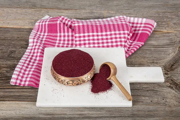 Tahta kaşıkta kuru baharatlı sumak. Yer sumac baharatı. Kurutulmuş kırmızı Sumac tozu, ahşap kaşıkta, kırsal masada sumak üzümlü baharatlar. Sağlıklı gıda konsepti.