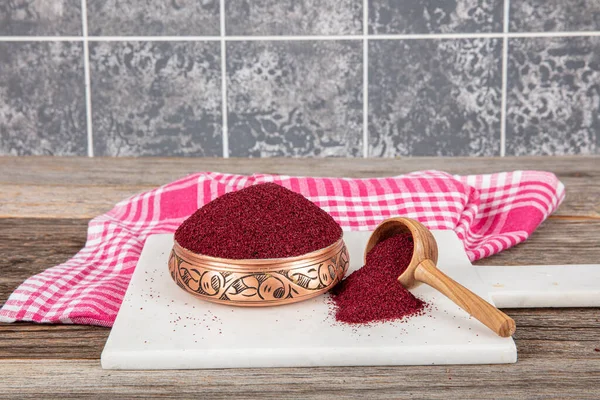 Tahta kaşıkta kuru baharatlı sumak. Yer sumac baharatı. Kurutulmuş kırmızı Sumac tozu, ahşap kaşıkta, kırsal masada sumak üzümlü baharatlar. Sağlıklı gıda konsepti.