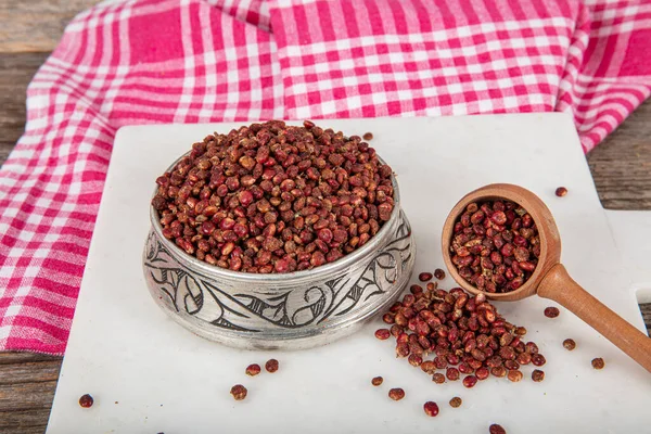 Tahta kaşıkta kuru baharatlı sumak. Yer sumac baharatı. Kurutulmuş kırmızı Sumac tozu, ahşap kaşıkta, kırsal masada sumak üzümlü baharatlar. Sağlıklı gıda konsepti.