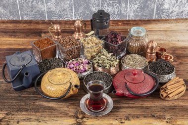 Tahta arka planda sıcak demlenmiş çayla dolu dökme demir çaydanlığın yanında farklı türde yeşil, siyah ve bitkisel çaylar. Lezzetli organik içecekler. Yukarıdan bak.