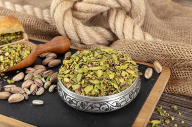 Şam fıstığı doğranmış fındık konsepti. Fıstıklar sunum için bakır kasede ve siyah mermer üzerinde hazırlandı. Toprak, Değirmen, Ezilmiş veya Granulated Pistachio Tozu.