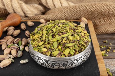 Şam fıstığı doğranmış fındık konsepti. Fıstıklar sunum için bakır kasede ve siyah mermer üzerinde hazırlandı. Toprak, Değirmen, Ezilmiş veya Granulated Pistachio Tozu.