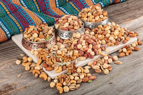 stock image Mixed snacks in a copper bowl. Background of various nuts (almonds, cashews, hazelnuts, peanuts, walnuts). Vegetarian meal. Healthy eating concept.