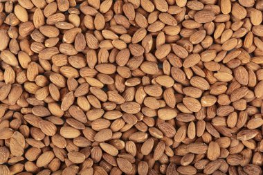 Beyaz arka planda izole edilmiş ceviz füme badem. Büyük çiğ bademlerden oluşan bir arka plan, rastgele yerleştirilmiş, vejetaryenler için kabuklu fındık..