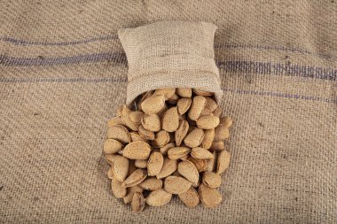 Kabuklu badem, sert kabuklu doğal organik badem yığını. Kabuklu çiğ badem. Topladıktan sonra kabuktaki badem yığınının yakın plan görüntüsü.