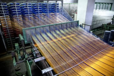 Modern halı dokuma fabrikası. Halı yapımı makine iğnesi. Halı dokuma makinesine bağlanmış iplik parçaları. Bir kumaş dokuma fabrikasının içinde..