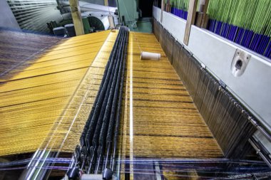 Modern halı dokuma fabrikası. Halı yapımı makine iğnesi. Halı dokuma makinesine bağlanmış iplik parçaları. Bir kumaş dokuma fabrikasının içinde..