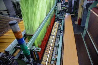 Modern halı dokuma fabrikası. Halı yapımı makine iğnesi. Halı dokuma makinesine bağlanmış iplik parçaları. Bir kumaş dokuma fabrikasının içinde..