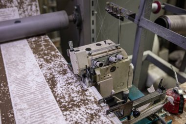 Halı dokuma fabrikasındaki halı kenarı tıkanmış. Endüstriyel dikiş makinesinin halısını diken fabrika işçisi..