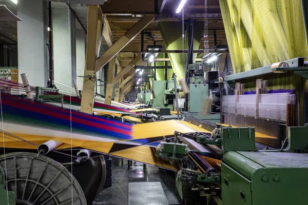 Synthetic yarns for carpet factory, carpet production, weaving looms. Interior of a Carpet Weaving Factory. Spool Sewing Thread Rack at Textile Weaving Mill.