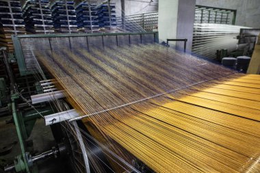 Halı fabrikası için sentetik iplikler, halı üretimi, dokuma tezgahları. Bir halı dokuma fabrikasının içinde. Tekstil Dokuma Değirmeninde Spool Dikiş Rafı.