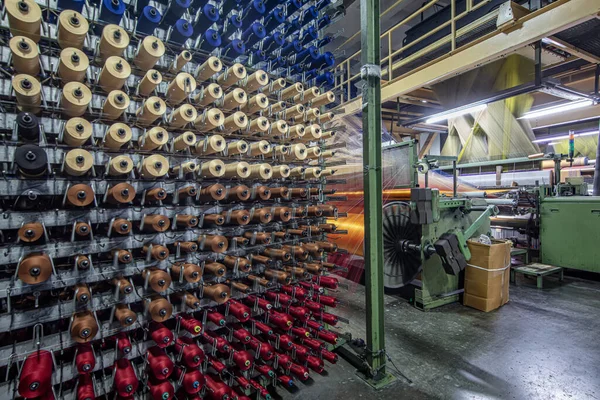 Synthetic yarns for carpet factory, carpet production, weaving looms. Interior of a Carpet Weaving Factory. Spool Sewing Thread Rack at Textile Weaving Mill.