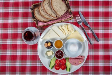 Türk Mutfağı Kahvaltı Tabağı. Dilimlenmiş kiraz domatesli beyaz kahvaltı tabağı, salatalık ve ahşap masada haşlanmış yumurta..
