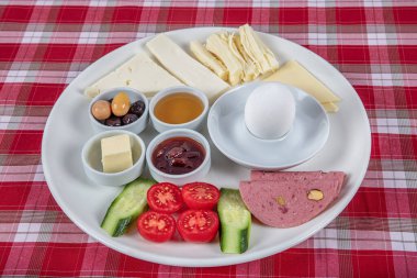 Türk Mutfağı Kahvaltı Tabağı. Dilimlenmiş kiraz domatesli beyaz kahvaltı tabağı, salatalık ve ahşap masada haşlanmış yumurta..