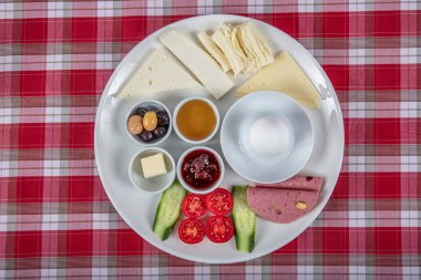 Türk Mutfağı Kahvaltı Tabağı. Dilimlenmiş kiraz domatesli beyaz kahvaltı tabağı, salatalık ve ahşap masada haşlanmış yumurta..