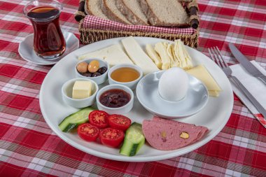 Türk Mutfağı Kahvaltı Tabağı. Dilimlenmiş kiraz domatesli beyaz kahvaltı tabağı, salatalık ve ahşap masada haşlanmış yumurta..