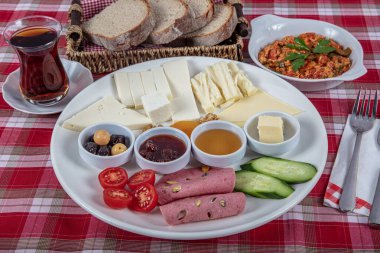 Türk Mutfağı Kahvaltı Tabağı. Dilimlenmiş kiraz domatesli beyaz kahvaltı tabağı, salatalık ve ahşap masada haşlanmış yumurta..