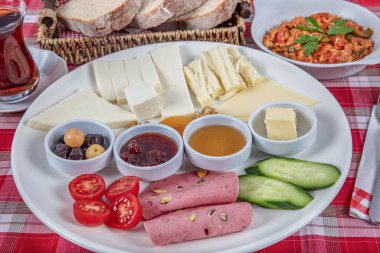 Türk Mutfağı Kahvaltı Tabağı. Dilimlenmiş kiraz domatesli beyaz kahvaltı tabağı, salatalık ve ahşap masada haşlanmış yumurta..