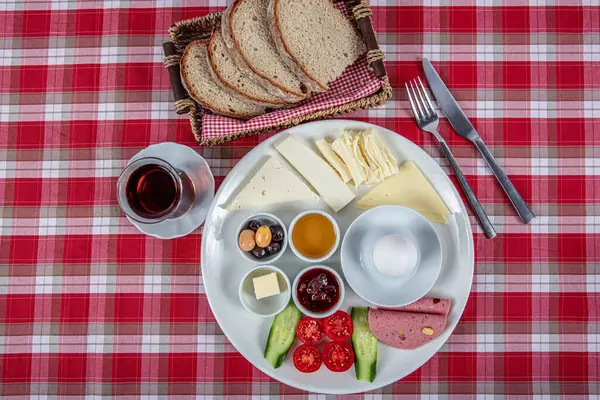 Türk Mutfağı Kahvaltı Tabağı. Dilimlenmiş kiraz domatesli beyaz kahvaltı tabağı, salatalık ve ahşap masada haşlanmış yumurta..