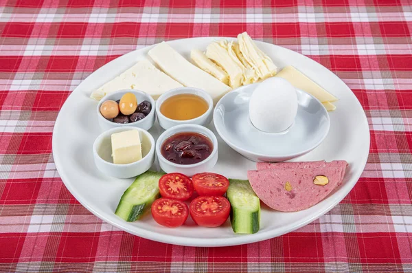 Türk Mutfağı Kahvaltı Tabağı. Dilimlenmiş kiraz domatesli beyaz kahvaltı tabağı, salatalık ve ahşap masada haşlanmış yumurta..
