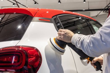 Usta arabayı cilalıyor. Göçüklerin mekanik olarak kaldırılması, araba tamircisinin otomobil gövde afişini öğütmesi..