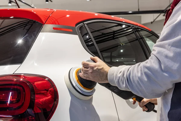 Usta arabayı cilalıyor. Göçüklerin mekanik olarak kaldırılması, araba tamircisinin otomobil gövde afişini öğütmesi..