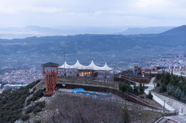 Denizli Türkiye - 26 Şubat 2024; Denizli Seyir Tepesi. Şehir ormanında inşa edilen ve Denizli şehrinin panoramik şehir manzaralı sembolü olan dev metal horoz.. 