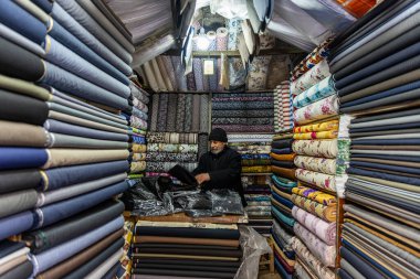 Mardin Türkiye 10 Ocak 2024; Mardin Türkiye 'deki mağaza satıcısı mağaza içinde satılık kumaşı ölçüyor. Kumaş dükkanında mendille çalışan bir satıcı. Küçük İş Konsepti.