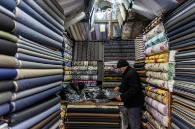 Mardin Türkiye 10 Ocak 2024; Mardin Türkiye 'deki mağaza satıcısı mağaza içinde satılık kumaşı ölçüyor. Kumaş dükkanında mendille çalışan bir satıcı. Küçük İş Konsepti.