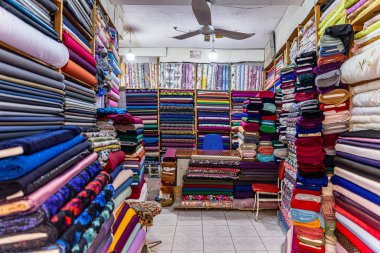 Mardin Türkiye 10 Ocak 2024; Mardin Türkiye 'deki mağaza satıcısı mağaza içinde satılık kumaşı ölçüyor. Kumaş dükkanında mendille çalışan bir satıcı. Küçük İş Konsepti.