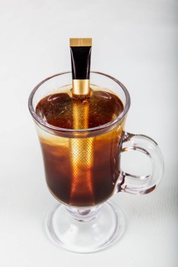 Bir bardak taze demlenmiş damlatılmış kahve. Kadın elleri cam bir fincanda demlenmiş bir kahve torbası tutuyor. Drip Brew Coffee 'nin üstüne dök.