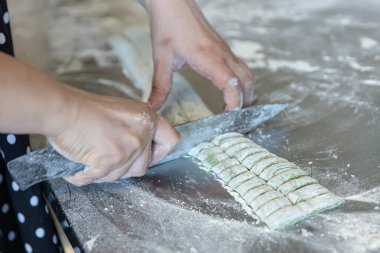 Ispanaklı yeşil makarna. Ispanaklı makarna. Kadın şef yeşil ıspanaklı makarna hamurunu fırının üstünde kaynayan bir tencereye atıp makarna pişiriyor..