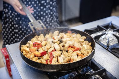 Şef mutfakta kremalı tavuk sote hazırlıyor. Kadın aşçı restoranın mutfağında büyük bir tavada tavuk sote hazırlar..