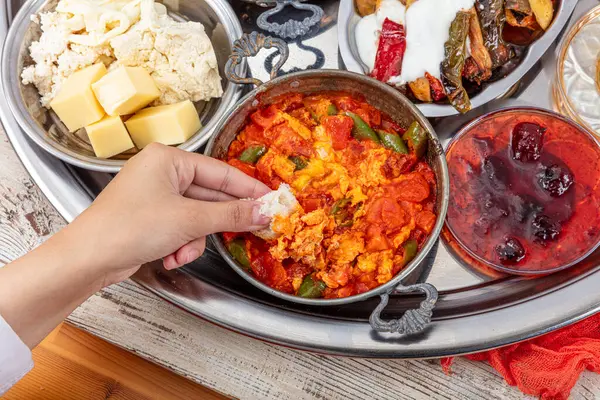 Geleneksel Türk Kahvaltı Masası (Serpme Kahvalti). Geleneksel Türk köyü kahvaltısı bakır tavada yumurta, menemen, bal pıhtılaşmış krema, ahşap masada peynir çeşitleri.