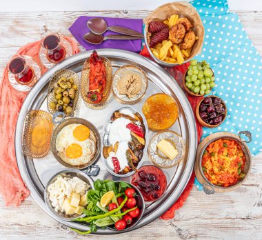 Geleneksel Türk Kahvaltı Masası (Serpme Kahvalti). Geleneksel Türk köyü kahvaltısı bakır tavada yumurta, menemen, bal pıhtılaşmış krema, ahşap masada peynir çeşitleri.