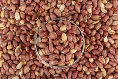 Tuzlu kavrulmuş fıstık. Ahşap zeminde yer fıstıkları. Yer fıstığı çekirdekleri. Bakır tabakta yer fıstığı.