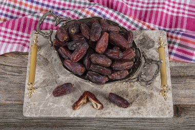 Medina date fruit. Close up shot of date fruit on marble tray in silver bowl on wooden table background. Dried date fruit is healthy as a snack. clipart