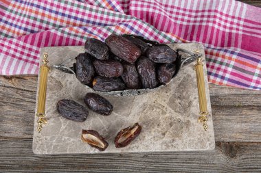 Büyük boy Kudüs Randevu meyvesi. Mermer tepside, ahşap masa arkaplanındaki gümüş kasede hurma meyvesi yakın çekim. Kuru hurma meyvesi atıştırmalık kadar sağlıklıdır..