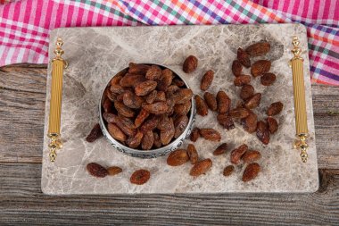 Çekirdekli sarı kuru üzüm. Bakır bir kasede kurutulmuş sarı kuru üzümler mermer tepside servis edilir, kuru üzümler bakır bir kuru üzüm kasesinin etrafına saçılır..