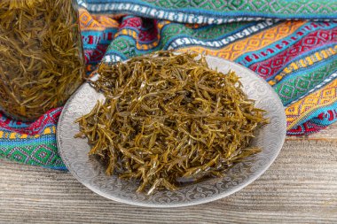 Taze zeytin yağlı yeşil salataları eklemek için zahter (Thymbra spicata) yaprakları kullanılır. Cam kavanozda zeytinyağı bulunan siyah kekik (zahter). Tahta arka planda Zahter. Akdeniz yemekleri.