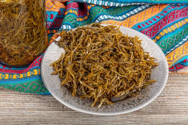 stock image Fresh leaves of the zahter (Thymbra spicata) used to add the green salads with olive oils. Black thyme (zahter) with olive oil in a glass jar. Zahter on wooden background. Mediterranean food.