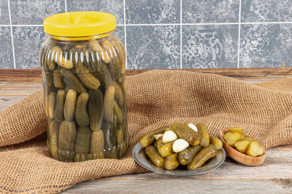 Pickled gherkins. Canned salted pickled cucumbers in a plastic jar. Homemade gherkin pickle plate. Autumn canned vegetables. Healthy homemade food.