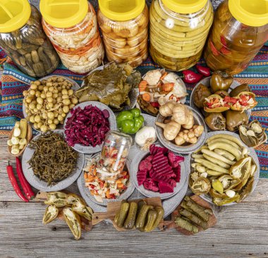 Ev yapımı turşu sergisi. Turşu kavanozu tipleri. Tahta masada farklı türde meyve ve sebze turşusu. Salatalık turşusu, domates, lahana, biber ve sarımsak, salatalık turşusu..