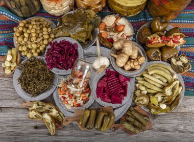 Ev yapımı turşu sergisi. Turşu kavanozu tipleri. Tahta masada farklı türde meyve ve sebze turşusu. Salatalık turşusu, domates, lahana, biber ve sarımsak, salatalık turşusu..