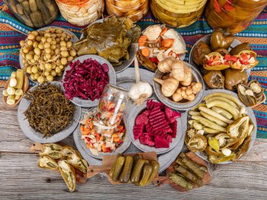 Ev yapımı turşu sergisi. Turşu kavanozu tipleri. Tahta masada farklı türde meyve ve sebze turşusu. Salatalık turşusu, domates, lahana, biber ve sarımsak, salatalık turşusu..