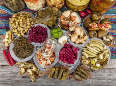 Ev yapımı turşu sergisi. Turşu kavanozu tipleri. Tahta masada farklı türde meyve ve sebze turşusu. Salatalık turşusu, domates, lahana, biber ve sarımsak, salatalık turşusu..