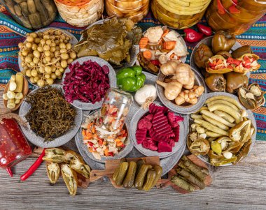 Ev yapımı turşu sergisi. Turşu kavanozu tipleri. Tahta masada farklı türde meyve ve sebze turşusu. Salatalık turşusu, domates, lahana, biber ve sarımsak, salatalık turşusu..